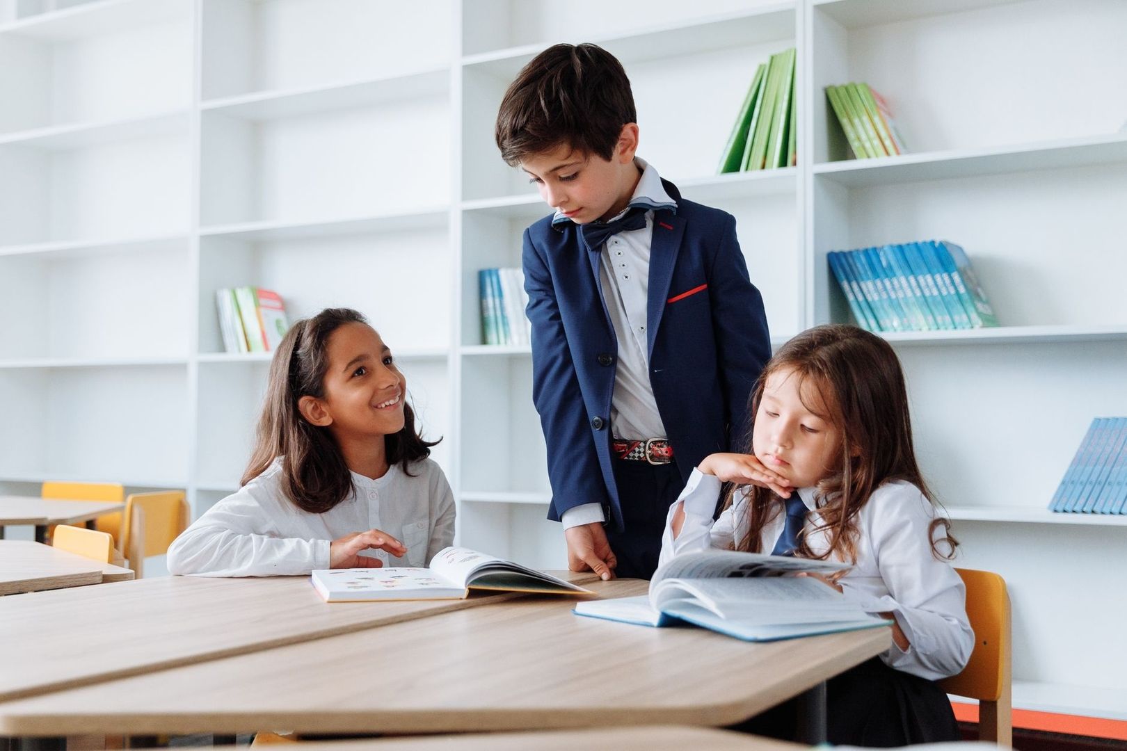 Three primary school children reading together at a classroom table